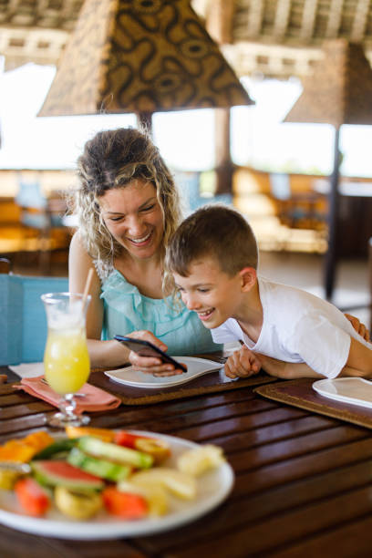 istock Happy mother and son using cell phone during lunch in a restaurant. 1451286894