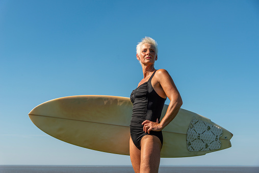Cropped shot of a senior woman holding a surfboard on her way to go surfing