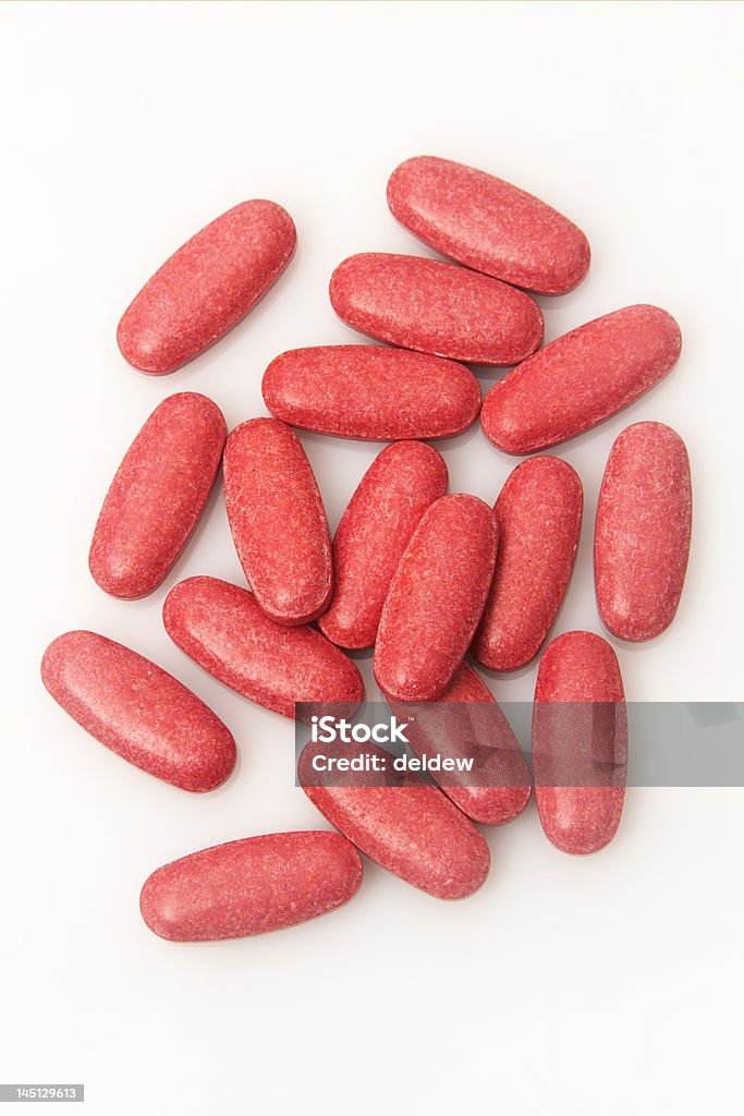 Scattered red vitamin tablets on a white surface Scattered red tablets on a white surface. Image is shot from above Antibiotic Stock Photo