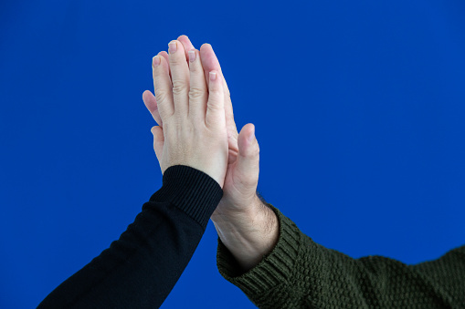 Giving five at office on blue background man's and woman's hands