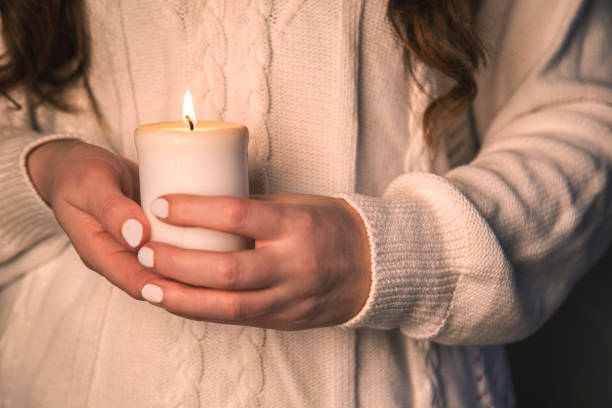 istock Hands with white manicure holds white candle 1451301862