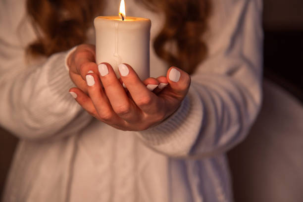 istock Hands with white manicure holds white candle 1451301926
