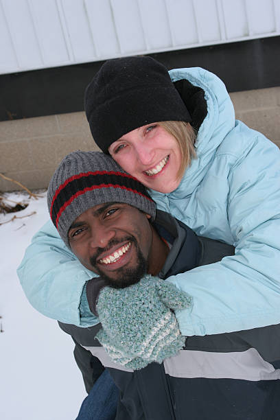 istock Multi racial couple on a happy winter piggy back ride 145130201