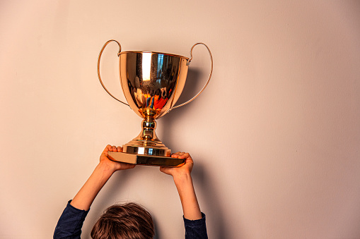 Champion cup in hands on beige background