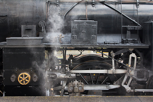 The steam locomotive is emitting smoke. Close up