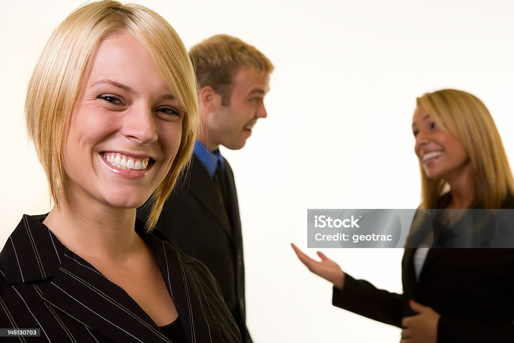 Business meeting Smiling attractive business woman in focus with two business people having a conversation behind her out of focus Beauty Stock Photo