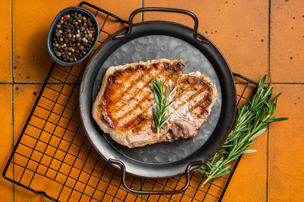istock Grilled pork T bone chop meat steak. Orange background. Top view 1451308449