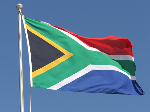 The wonderful South African flag in front of a clear blue sky.