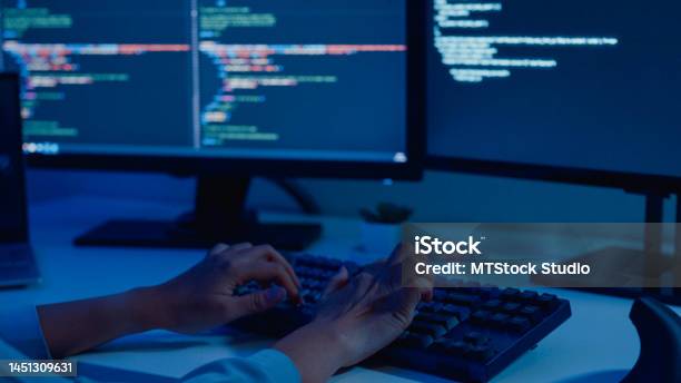 Closeup Of Young Asian Woman Software Developers Using Computer To Write Code Sitting At Desk With Multiple Screens Work Remotely In Home At Night Stock Photo - Download Image Now