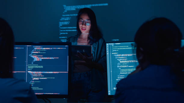 Young Asian woman software developers mentor leader manager talking to executive team analyzing source code in office at night. Young Asian woman software developers mentor leader manager talking to executive team analyzing source code in office at night. Programmer development concept. javascript stock pictures, royalty-free photos & images