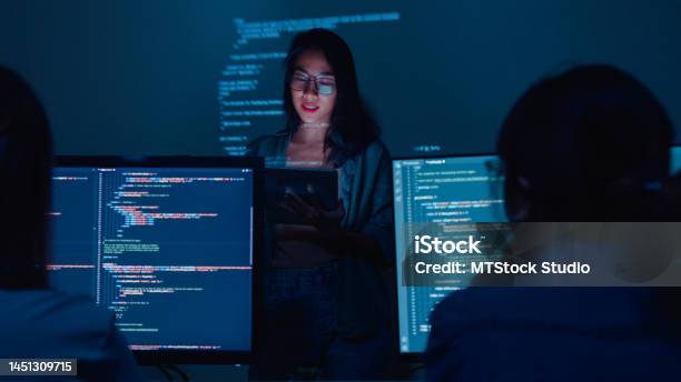 Young Asian Woman Software Developers Mentor Leader Manager Talking To Executive Team Analyzing Source Code In Office At Night Stock Photo - Download Image Now