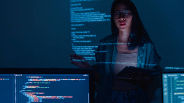 istock Young Asian woman software developers mentor leader manager talking to executive team analyzing source code in office at night. 1451309734
