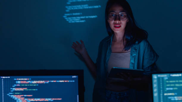istock Young Asian woman software developers mentor leader manager talking to executive team analyzing source code in office at night. 1451309741