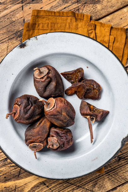 istock Natural Sun Dried persimmon fruit on a plate. Wooden background. Top view 1451310239
