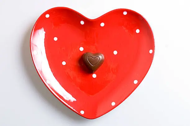 Chocolate heart on a red polka dot plate. 