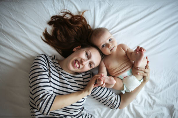 Gentle mother hipster and baby 6 months, care Gentle mother hipster and baby 6 months, tenderness and care, top view. The concept of motherhood and happiness with the baby. Single mom and baby half dozen babies stock pictures, royalty-free photos & images