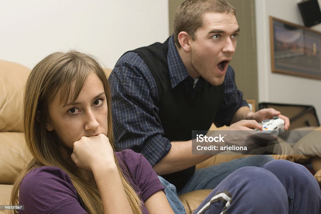 Bad Date Young woman very bored and annoyed while her bad date plays video games.  Addict Stock Photo
