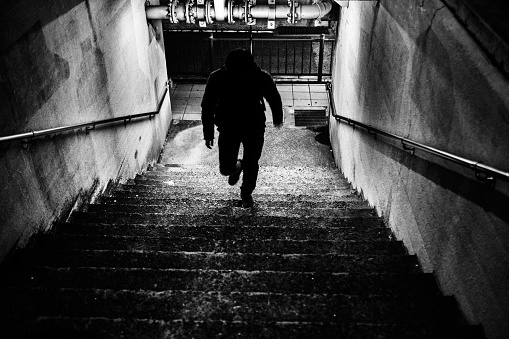Silhouette of a person running up the stairs from the underpass to the ground