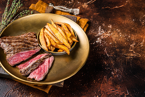 Elk steak with herbs and french fry, game meat. Dark background. Top view. Copy space