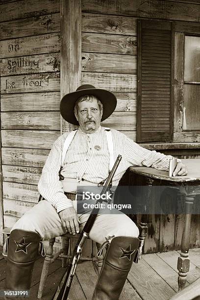 Weary Alter Cowboysheriff Sitzbereich Mit Gewehr Auf Verwitterten Veranda Stockfoto und mehr Bilder von Cowboy