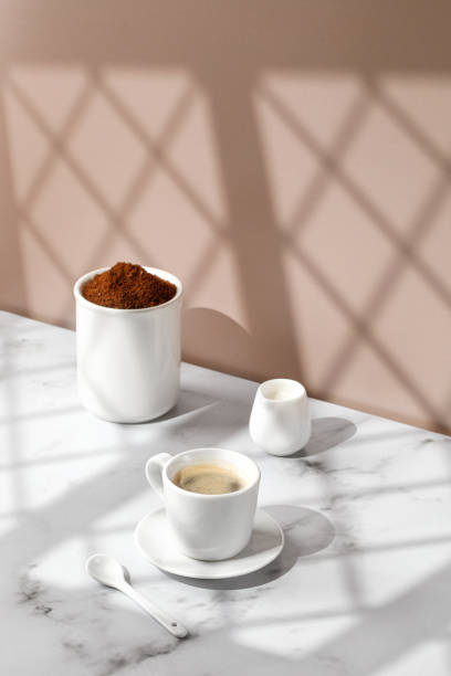 istock Coffee cup, hot drink in a mug. Beige and marble background with window shadow. Sunny, sunshine. Cappuccino in coffee cup. Still life. 1451321833