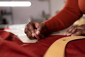 Close up of African American tailor using chalk for textile measurement drawing.