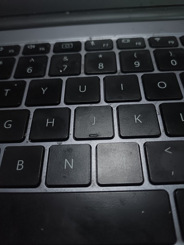 A close-up of a modern laptop computer keyboard. The computer is silver with black keys.