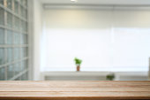 Empty wooden table against blurred bright modern home office in background. Copy space for your advertise design.