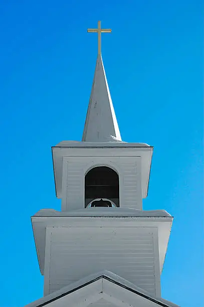 A church steeple, covered in snow, against a blue sky.