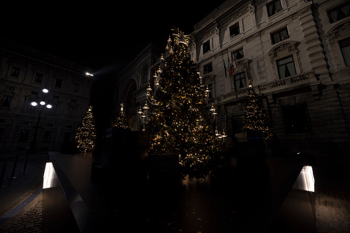Milan, Italy - December 22, 2022: street view of a Christmas tree in Piazza alla Scala during night time, no people are visible.