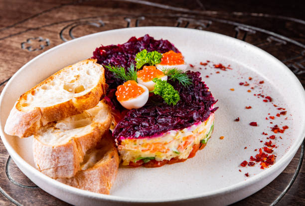 istock Layered salad with salmon, beets, carrots, onions, potatoes and eggs on a plate. 1451336791