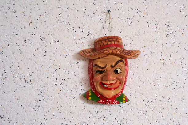 Collecting mask. Carnival decoration isolated on white wallpaper. Small funny larva head. Disguise for the fifth season. Hanger for the wall. Saulgau.