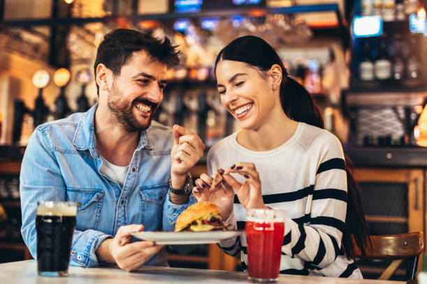ハンバーガーを食べ、ビールを飲む若い夫婦 - burger hamburger food fast food ストックフォトと画像