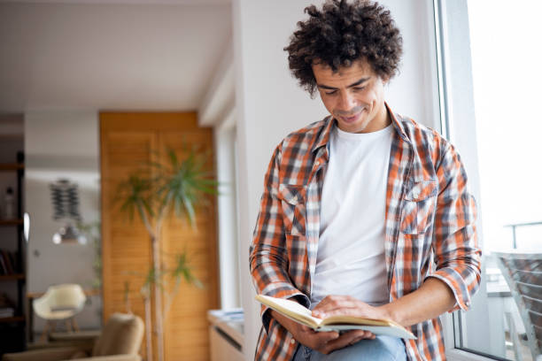 istock Man reading a book at home 1451348731