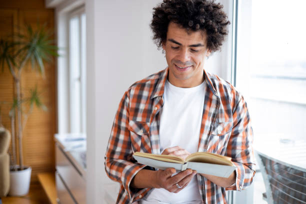 istock Man reading a book at home 1451348788