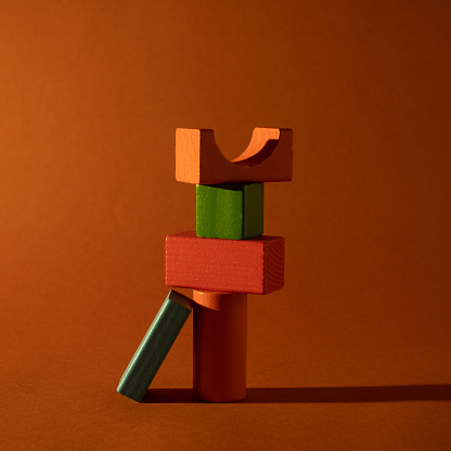 Create a balance with different wooden forms of combined colors to form an abstract building unit on the background