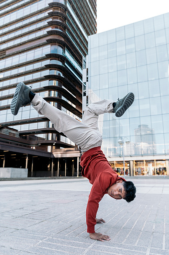 Cool break dancer practicing in the street and having fun. He is dancing and looking at camera.