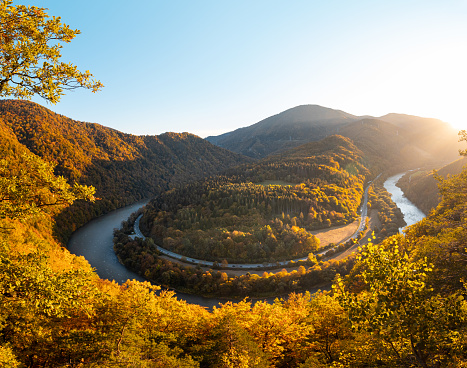 View of autumn scenery of Domasinsky meander illuminated with sunset light in Zilina region, Slovakia. The Vah River flows past autumn forests in a U-shape.