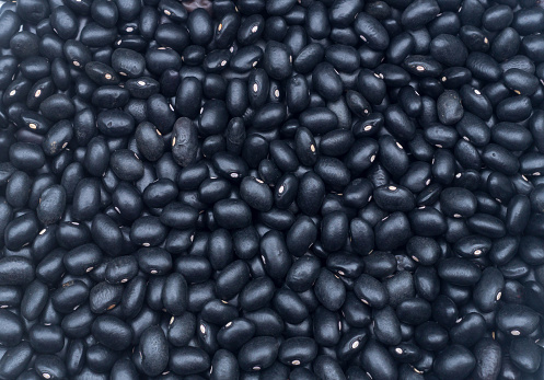 Photo of many seeds of fresh beautiful organic black bean in flat laying is taken for use as background or texture in art decoration work.
