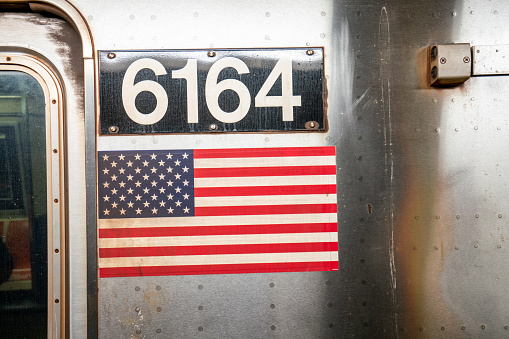 Detail of a subway train in New York City with USA flag. 6164 license plate. MTA New York City Subway.