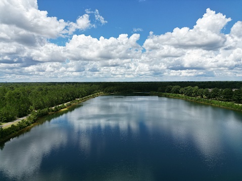 A beautiful view of a lake surrounded by trees under a blue cloudy sky.
