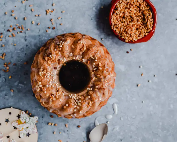 Overhead view of a bundt cake topped with sugar frosting and caramelized nuts