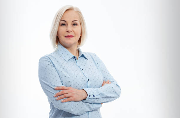 istock Middle aged businesswoman with folded arms on grey background 1451367788