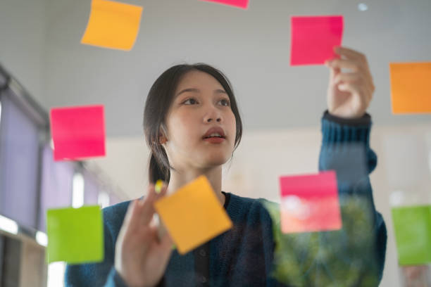 istock Confident businesswoman planning while looking at adhesive notes stuck on a glass wall. 1451369175