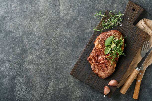 filetes. filete de carne a la parrilla en rodajas de nueva york o chuletón con especias romero y pimienta sobre tablero de mármol negro sobre fondo de madera vieja. vista superior. maqueta. - pot roast fotografías e imágenes de stock