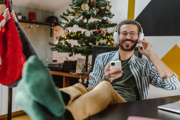 istock Relaxed man in cozy Christmas atmosphere using a smart phone 1451374583