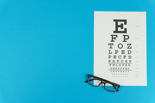 Glasses and a vision test table on the right on a blue background. High quality photo
