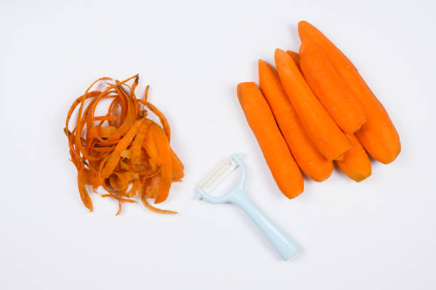 istock Peeled carrots, vegetable peeler and vegetable peelings on a white background.Cleaning vegetables 1451380249
