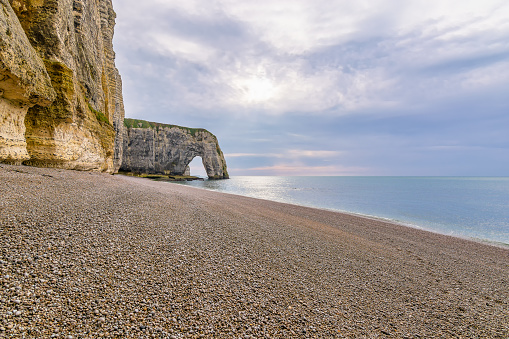 Scenic view of Etretat cliffs in Normandy France with pebble beach against dramatic sky