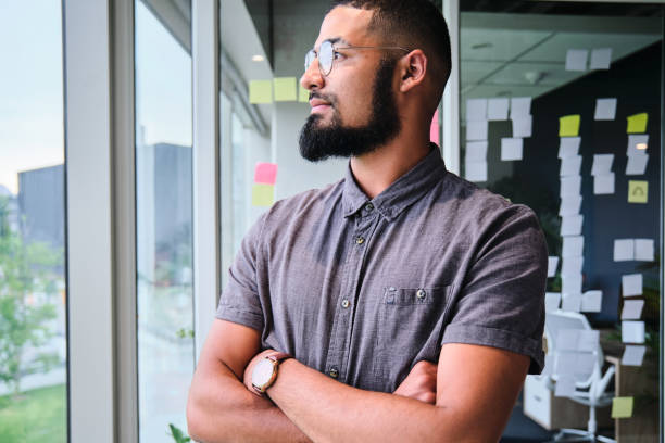 istock Young businessman looking out through a window in an office 1451385590